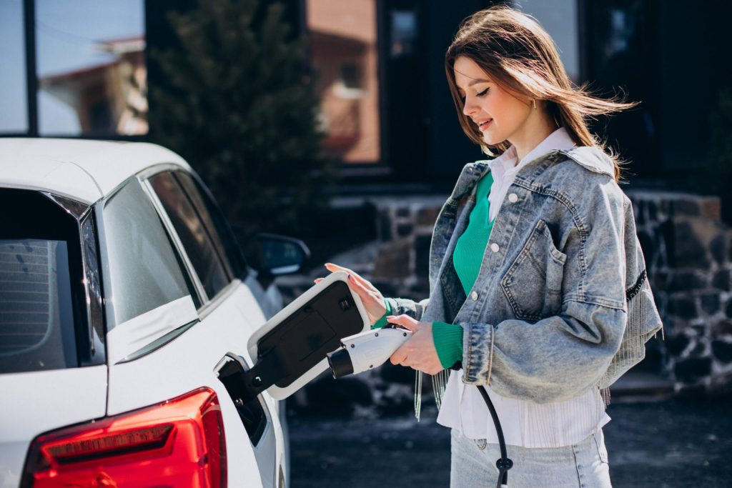 Woman using CITA EV Charger to plug in electric vehicle at home.