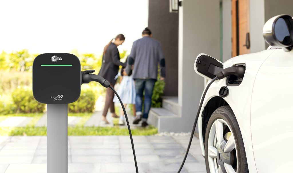 The image shows a black "Smart EV Charger" from "CITA" mounted on a grey pole, with a green light glowing.