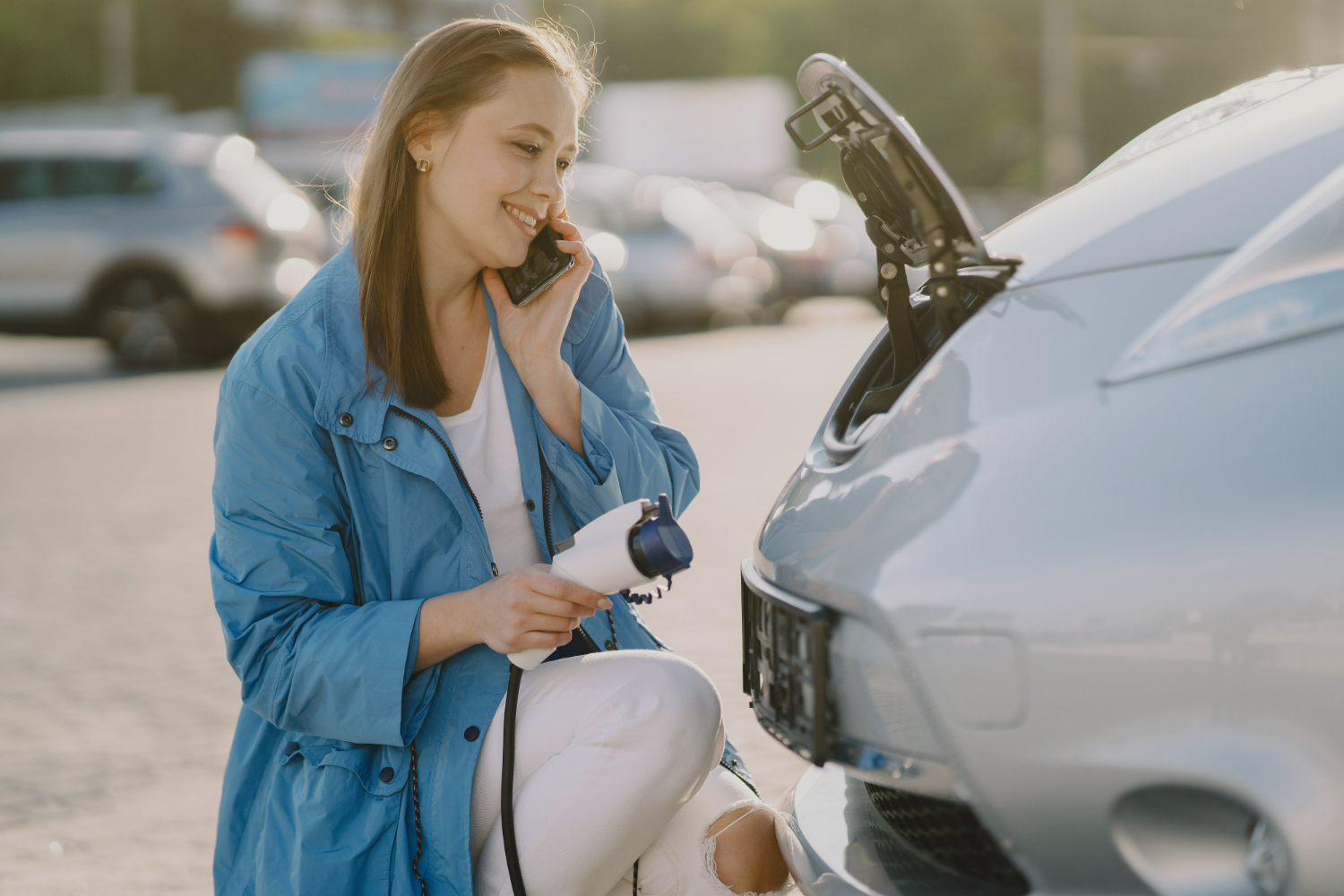 Woman preparing to charge her electric vehicle while talking on the phone, symbolizing user-friendly EV charging experience powered by OCPP for enhanced connectivity and real-time monitoring.