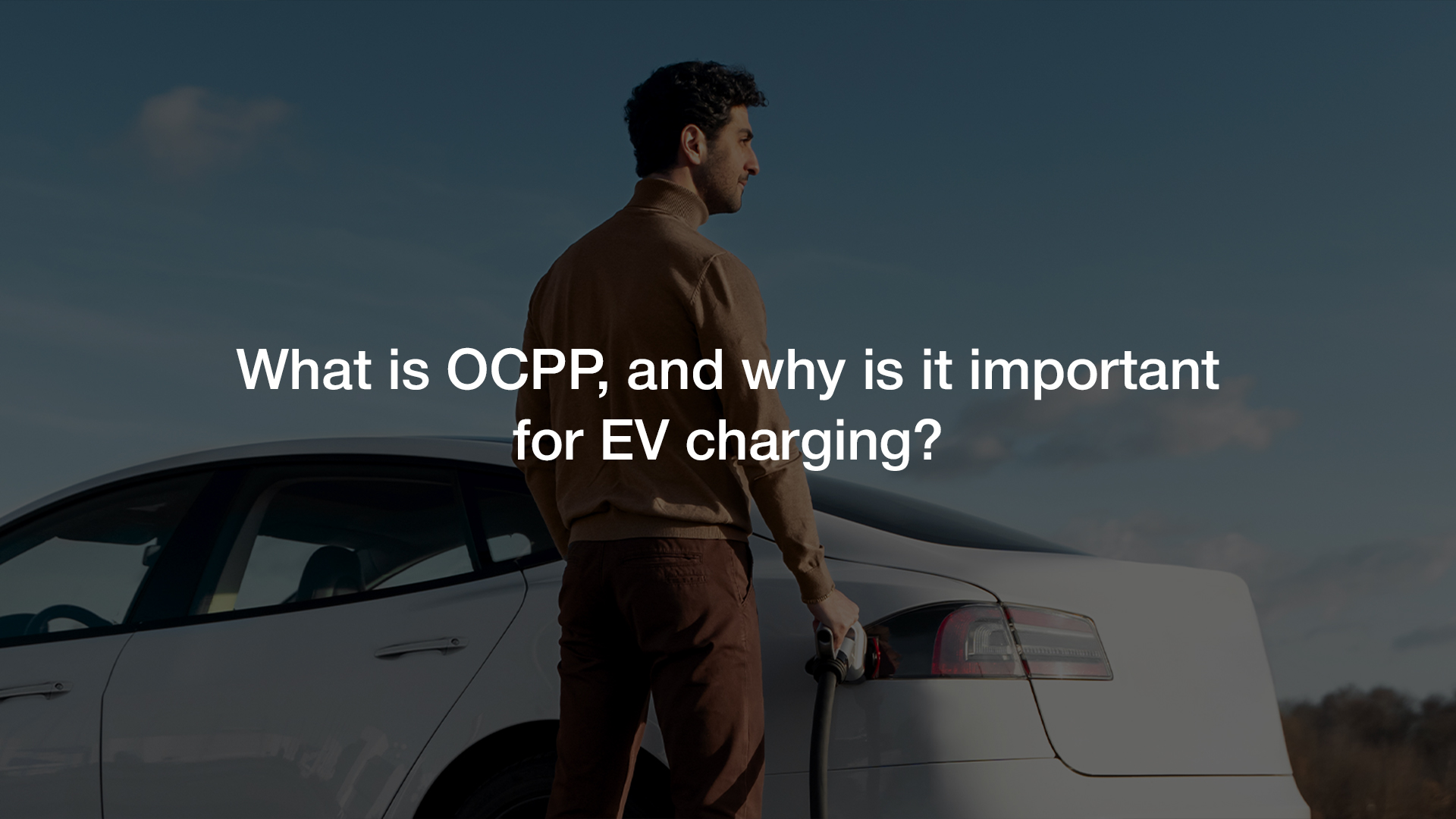 Man charging his electric vehicle with text overlay asking “What is OCPP, and why is it important for EV charging?”, illustrating the relevance of OCPP in modern EV charging infrastructure.